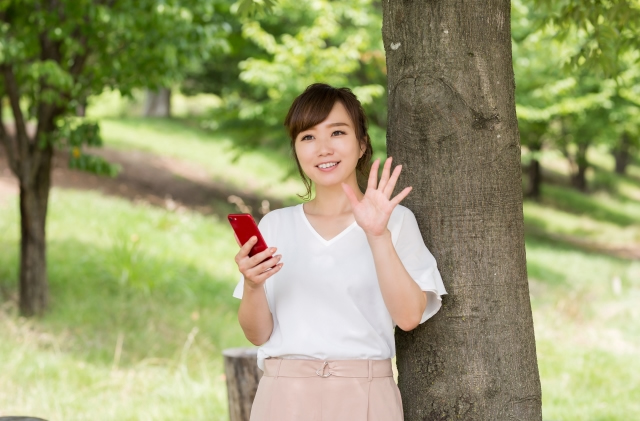 木漏れ日の中で、手を振る女性