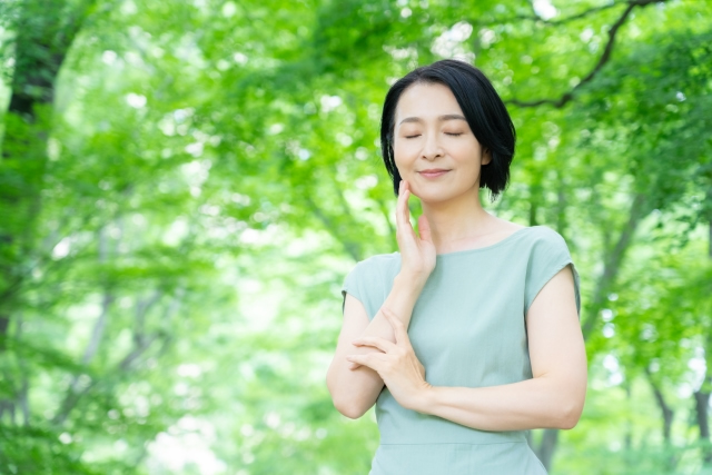 樹木を背景に考える女性