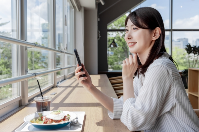 スマホを見ながら遠くを見る女性